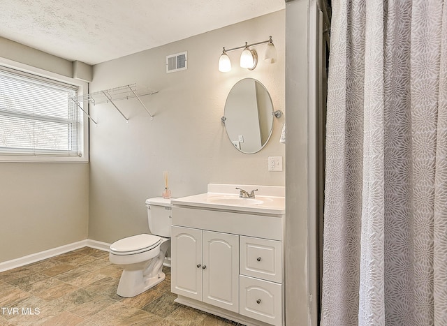 full bath featuring visible vents, baseboards, toilet, vanity, and a textured ceiling