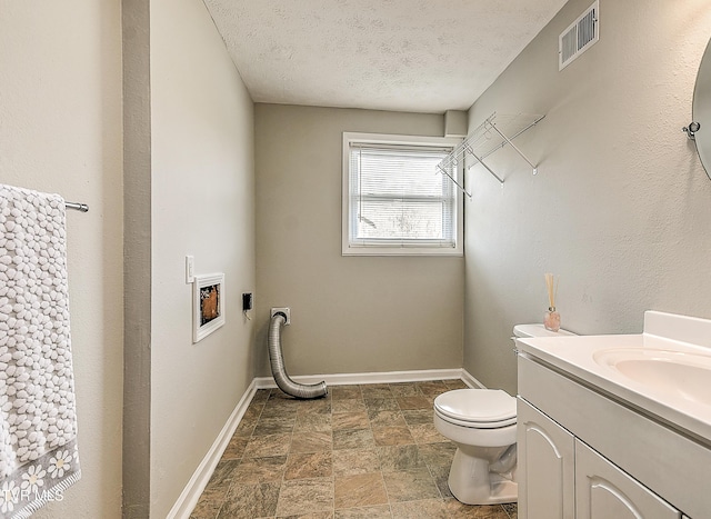 half bath featuring visible vents, toilet, a textured ceiling, baseboards, and vanity