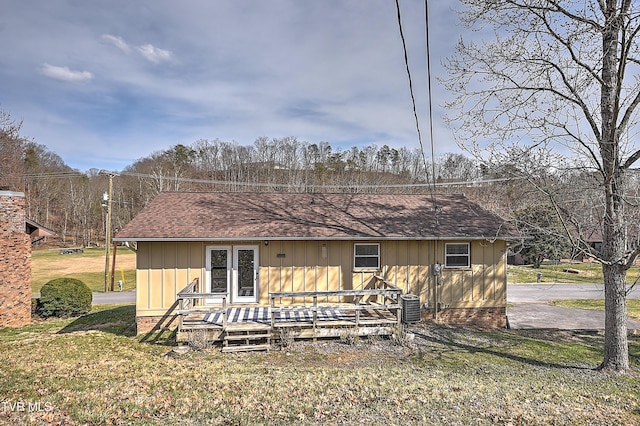 rear view of house with central air condition unit, a yard, roof with shingles, and a wooden deck