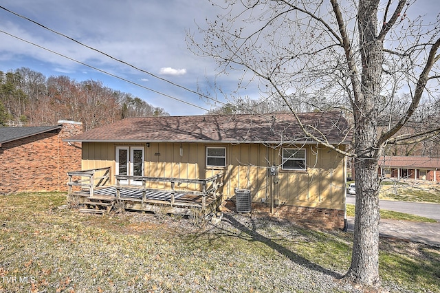 rear view of house featuring board and batten siding, central air condition unit, french doors, a yard, and a deck