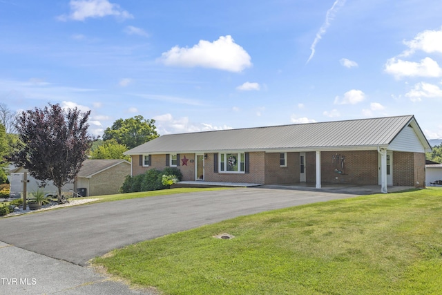 ranch-style home featuring brick siding, a front yard, an attached carport, and driveway