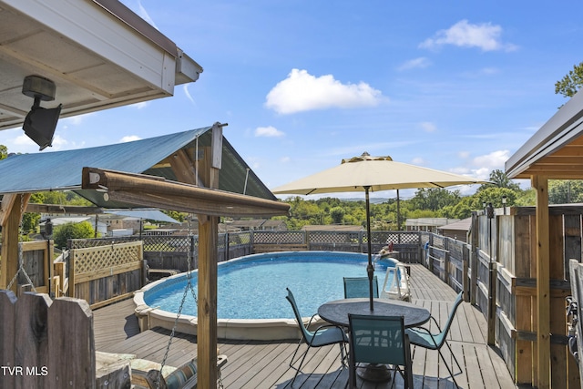 view of swimming pool featuring a deck, outdoor dining space, and a fenced in pool