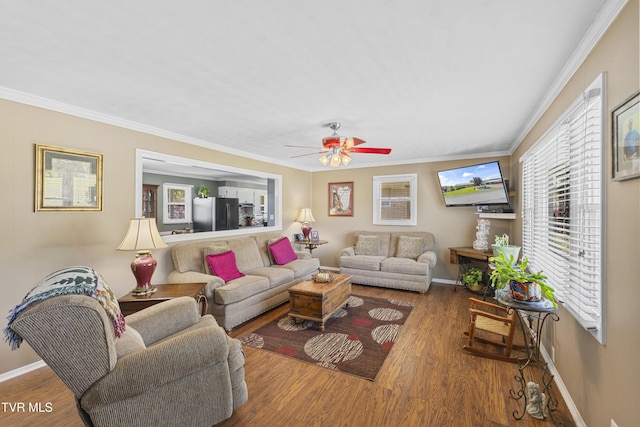 living area with baseboards, crown molding, a ceiling fan, and wood finished floors