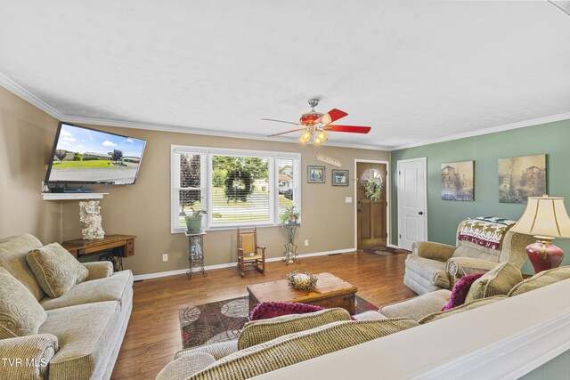 living area with baseboards, wood finished floors, a ceiling fan, and ornamental molding