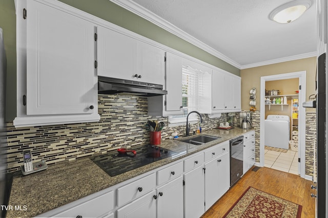 kitchen featuring under cabinet range hood, ornamental molding, washer / dryer, black appliances, and a sink