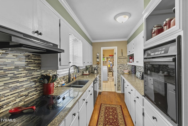 kitchen featuring oven, a sink, under cabinet range hood, dishwasher, and crown molding