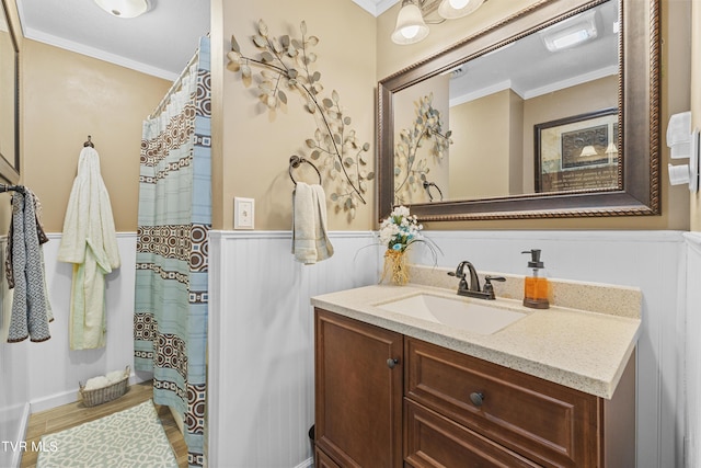 bathroom with a wainscoted wall, vanity, wood finished floors, and crown molding