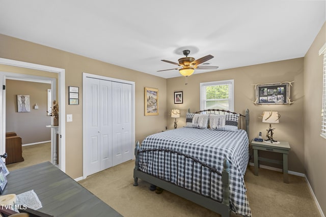 bedroom featuring a closet, light colored carpet, a ceiling fan, and baseboards