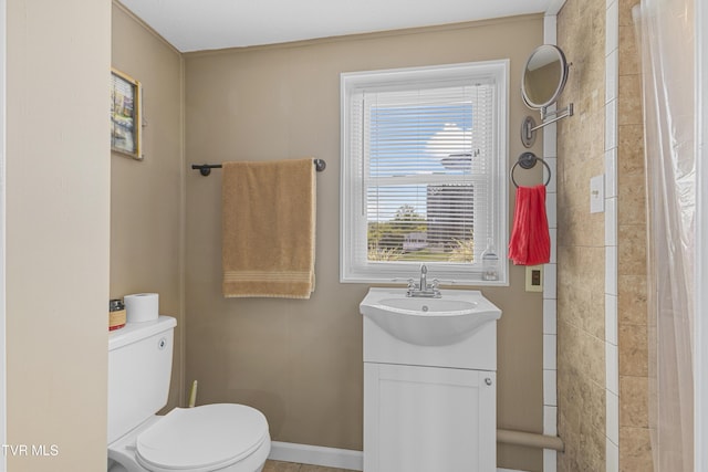 bathroom featuring tiled shower, toilet, vanity, and baseboards