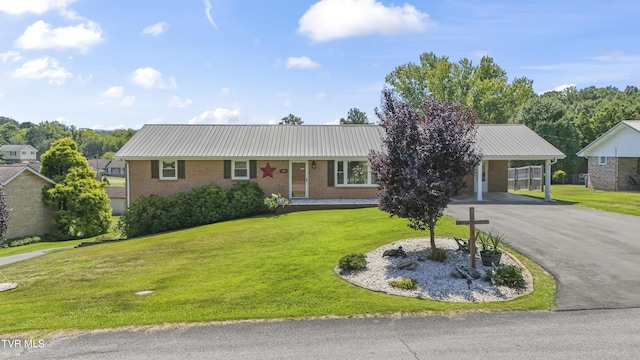 ranch-style home featuring driveway, a front lawn, metal roof, a carport, and brick siding