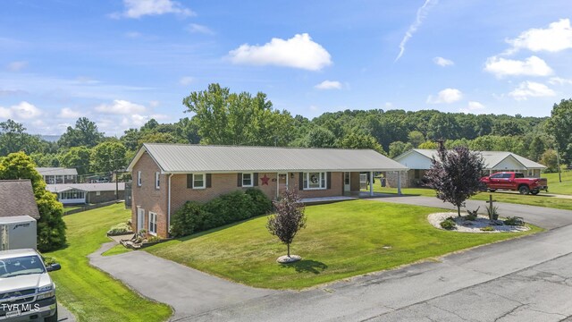 single story home featuring brick siding, an attached carport, concrete driveway, and a front lawn