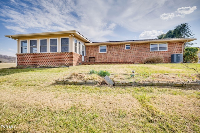 view of front facade with a front lawn, brick siding, and central AC