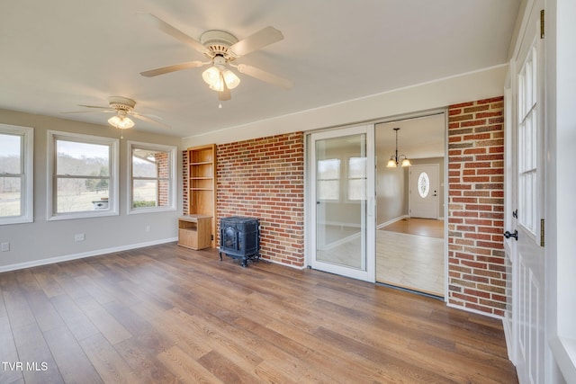 unfurnished sunroom with a wood stove and ceiling fan with notable chandelier