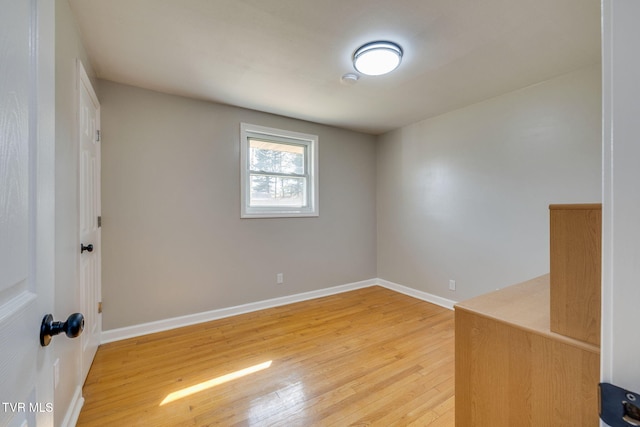 spare room featuring baseboards and light wood finished floors