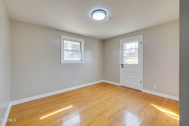 spare room featuring baseboards and light wood-style floors