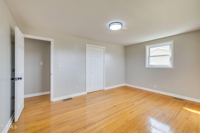 unfurnished bedroom featuring light wood-type flooring, visible vents, baseboards, and a closet