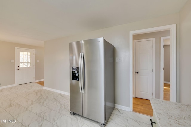 kitchen featuring light countertops, baseboards, stainless steel refrigerator with ice dispenser, and marble finish floor