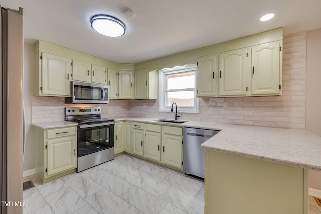 kitchen with a peninsula, a sink, decorative backsplash, stainless steel appliances, and marble finish floor