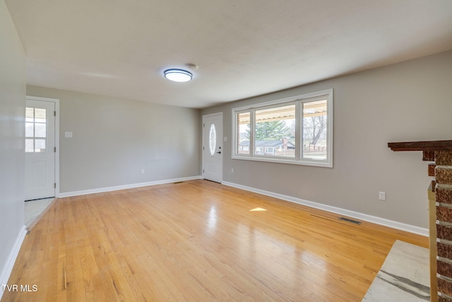 unfurnished living room with light wood-type flooring, visible vents, baseboards, and a healthy amount of sunlight