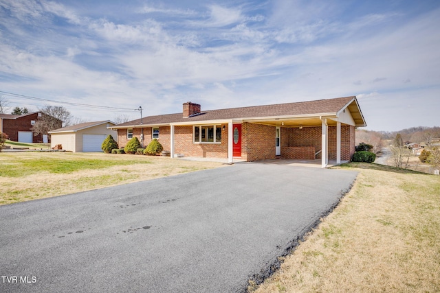 single story home with an outbuilding, aphalt driveway, a front yard, brick siding, and a chimney