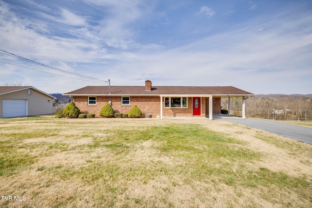 ranch-style house featuring brick siding, driveway, a front lawn, an attached carport, and a chimney