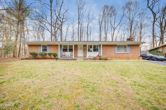 ranch-style home featuring brick siding, a chimney, covered porch, and a front yard