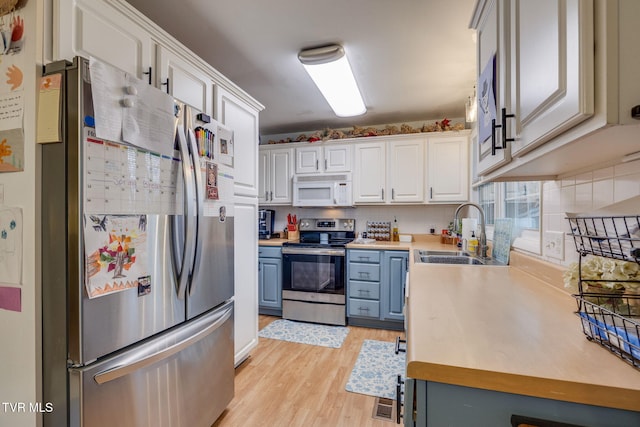4511 Grace Dr, Kingsport, TN 37664 - kitchen with light wood finished floors, light countertops, appliances with stainless steel finishes, white cabinetry, and a sink
