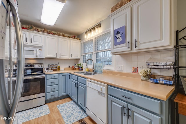 4511 Grace Dr, Kingsport, TN 37664 - kitchen with light wood finished floors, stainless steel appliances, white cabinetry, blue cabinets, and a sink