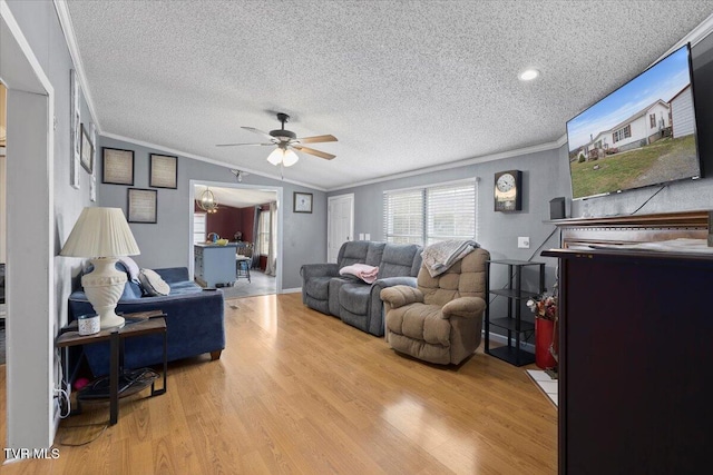 living area with a textured ceiling, wood finished floors, a ceiling fan, and ornamental molding