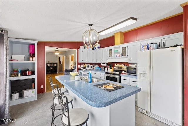 kitchen featuring an island with sink, a sink, a textured ceiling, white cabinetry, and appliances with stainless steel finishes