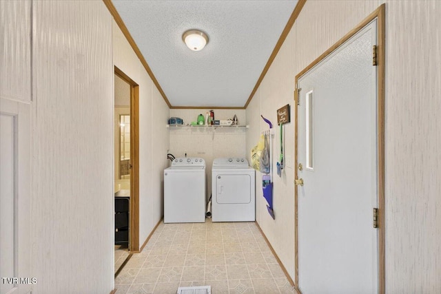 laundry room featuring washer and dryer, a textured ceiling, ornamental molding, and laundry area