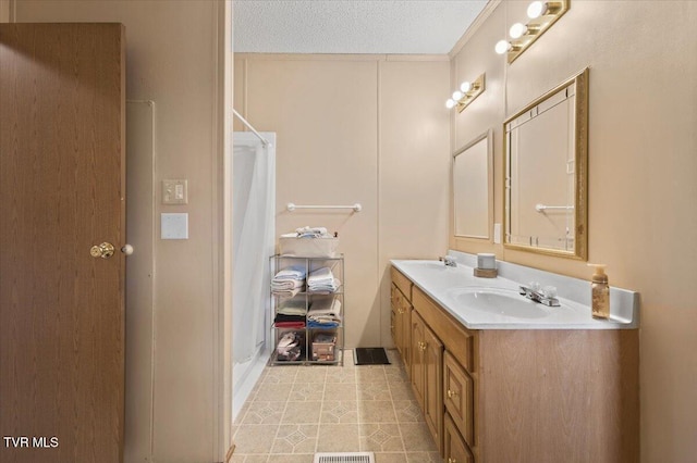 full bath with double vanity, curtained shower, a textured ceiling, and a sink