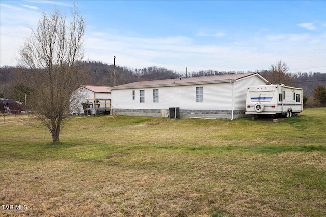 back of house with metal roof, a yard, and central AC