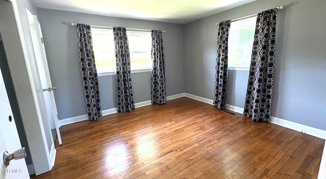 empty room with baseboards, visible vents, and hardwood / wood-style floors