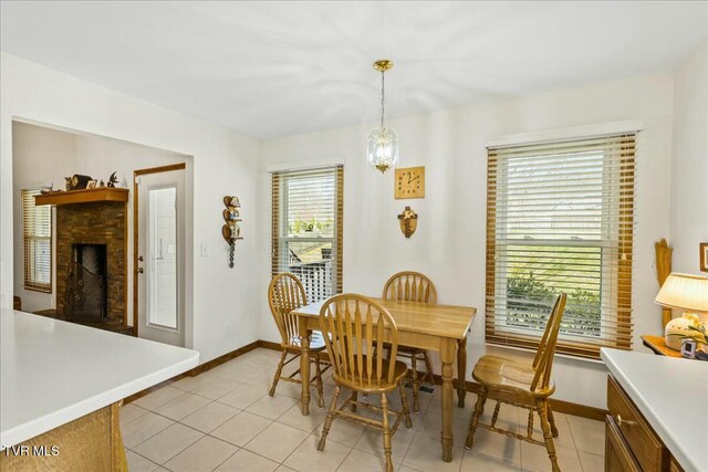 dining space with light tile patterned floors, a brick fireplace, and baseboards