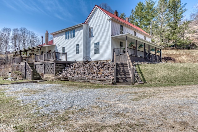 view of side of property with covered porch, a chimney, and stairs