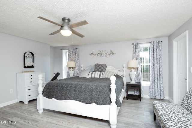 bedroom featuring ceiling fan, baseboards, a textured ceiling, and wood finished floors