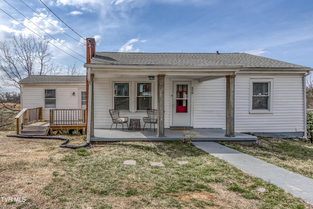 bungalow-style home featuring a front lawn, a porch, roof with shingles, and a chimney