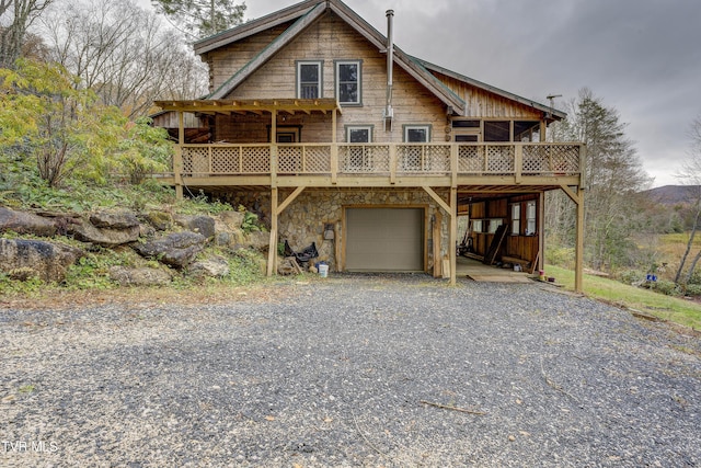 368 Ripshin Lake Rd, Roan Mountain, TN 37687 - view of front of house with an attached garage, stone siding, a deck, and driveway