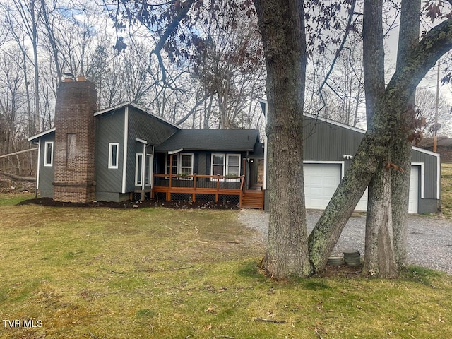 view of front facade featuring a front yard, a chimney, driveway, a deck, and an attached garage