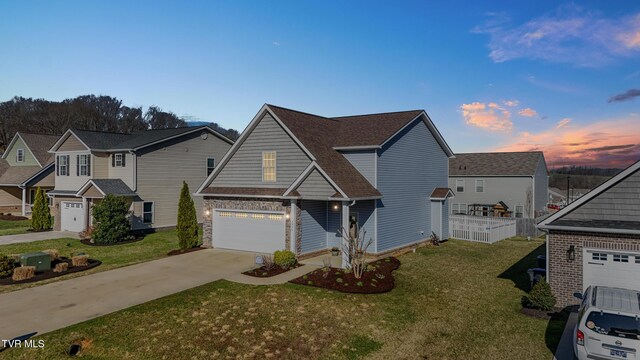view of front of house featuring fence, driveway, a shingled roof, a garage, and a lawn