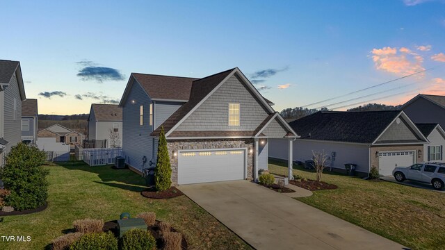 view of front of house featuring a front yard, fence, an attached garage, concrete driveway, and stone siding
