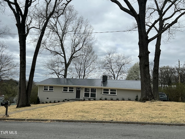 single story home featuring a front lawn, a chimney, and metal roof