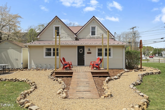 back of property with an outbuilding, a shed, metal roof, and a deck