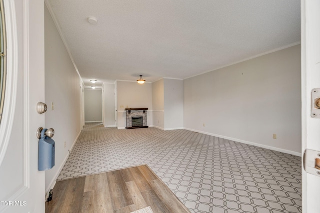 unfurnished living room featuring a glass covered fireplace, a textured ceiling, crown molding, and baseboards