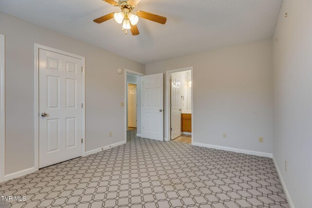 unfurnished bedroom featuring ceiling fan, ensuite bath, and baseboards