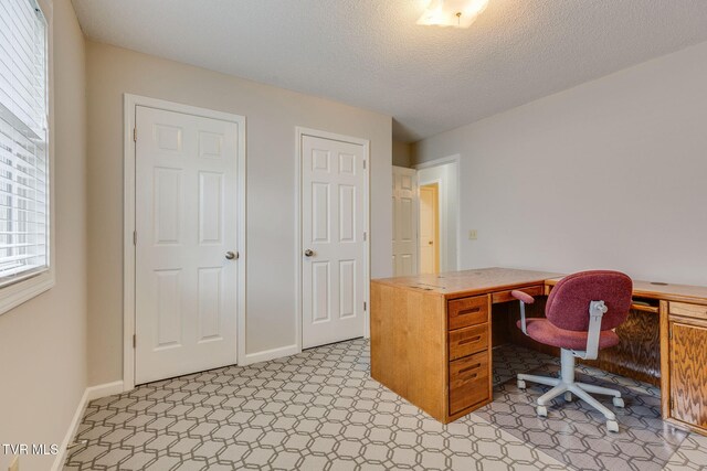 home office featuring light floors, baseboards, and a textured ceiling