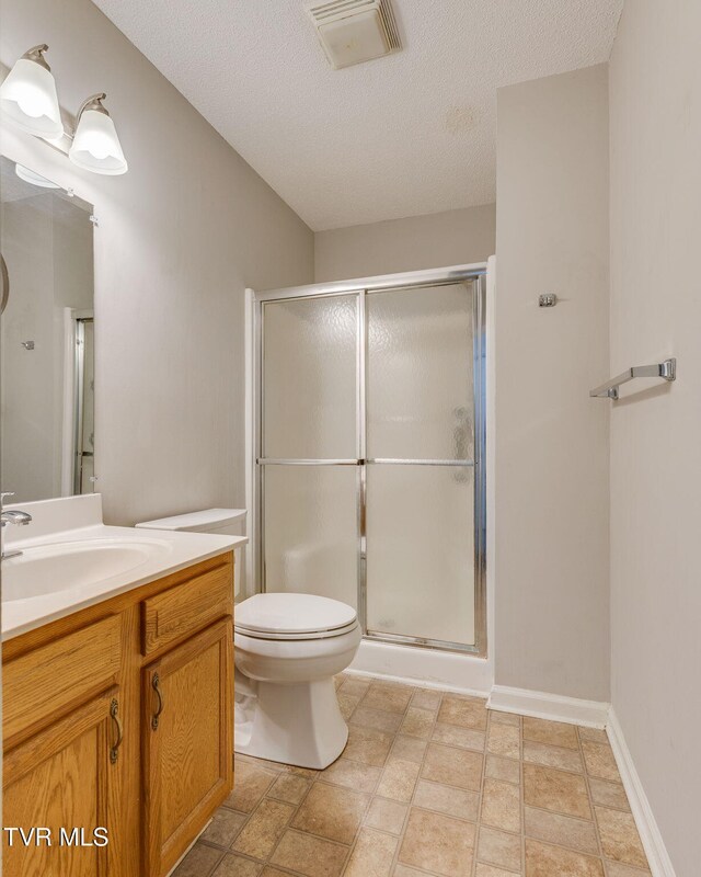 full bathroom with visible vents, a textured ceiling, a shower stall, baseboards, and vanity