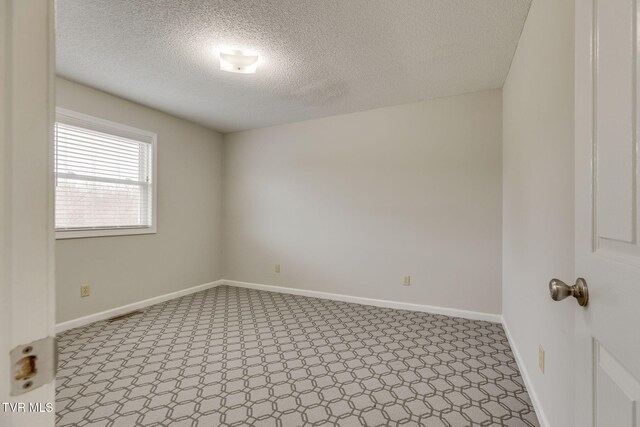 unfurnished room with a textured ceiling and baseboards
