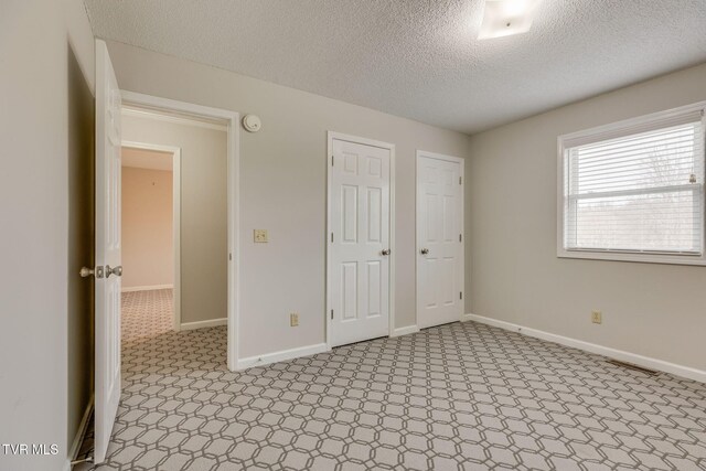 unfurnished bedroom featuring baseboards and a textured ceiling